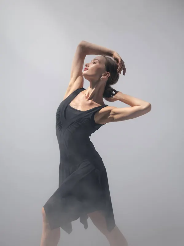 Zuza in a black dress in soft studio mist, one arm over her head