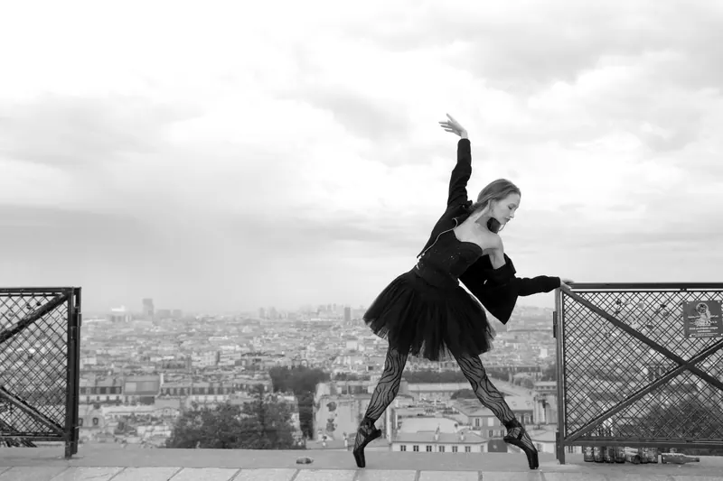 Zuza in black on a Paris rooftop, one arm curved above her head