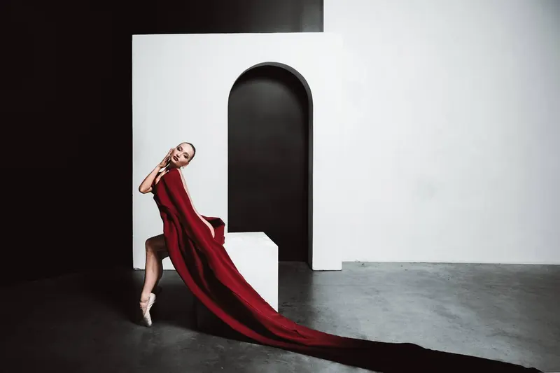 Zuza in a long red fabric in a white studio with an arch